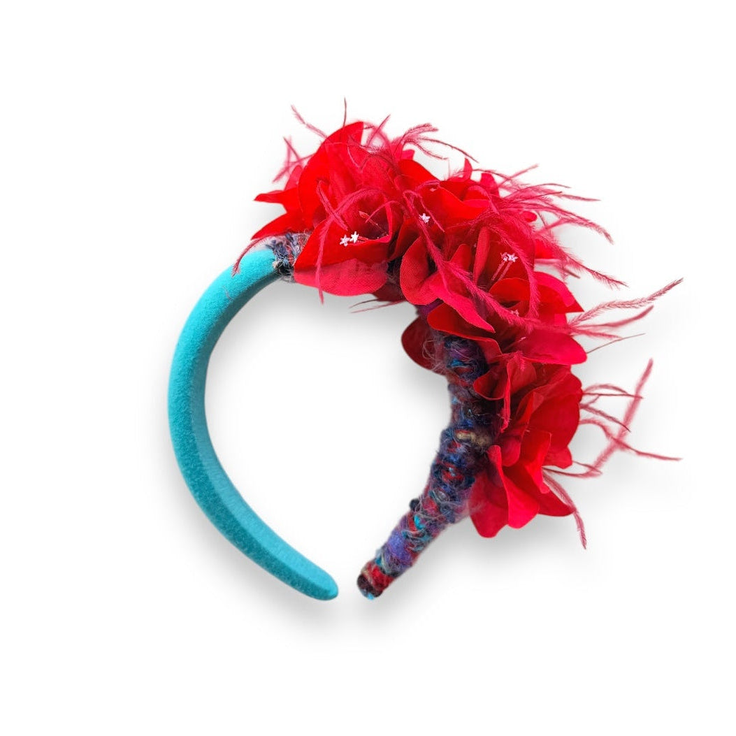 Handcrafted Red Bougainvillea Statement Headband with vivid red fabric flowers, red ostrich feathers, colourful yarn detailing and a turquoise velvet padded headband.