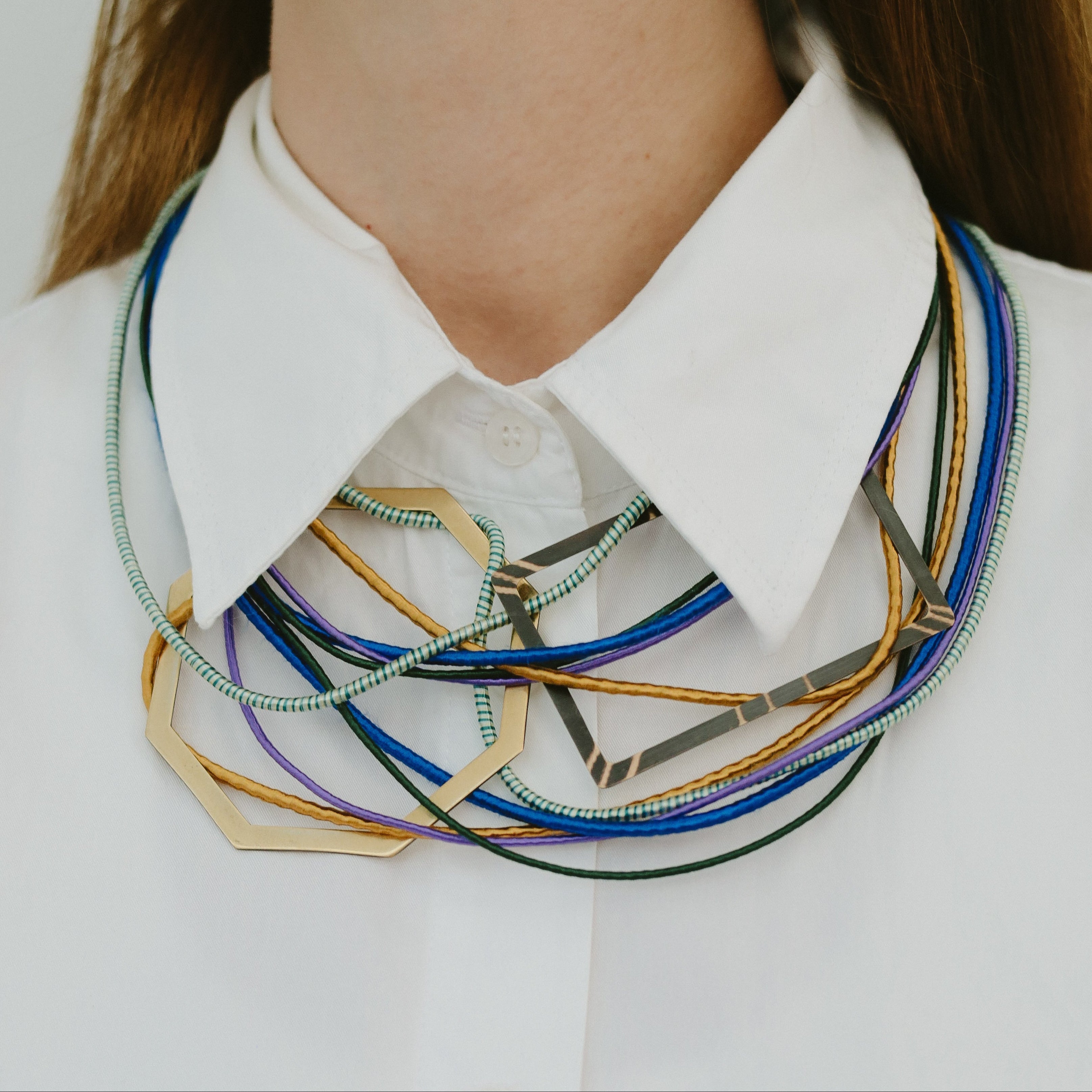 Close-up of a person wearing a white shirt with a colorful neckpiece.